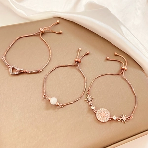 Detail of rose gold adjustable bracelets with heart and star charms on silk