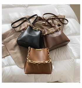 Three bucket bags in black, dark brown, and caramel with chunky gold chain decoration