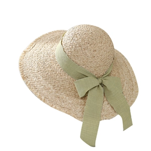 Summer wide brim raffia sun hat with green ribbon bow and frayed edges for beach vacations