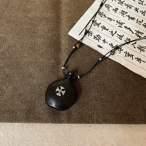 Détail du pendentif cœur en ébène vintage avec croix en argent et perles œil de tigre
