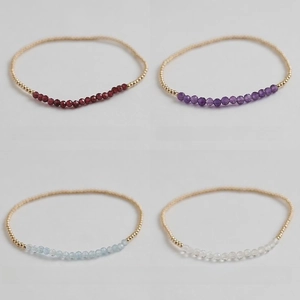 Detailed close-up of handmade gold beaded bracelets with natural amethyst and garnet stones