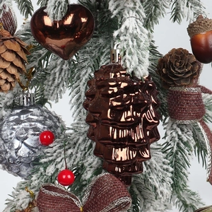 Brown pinecone and heart ornaments with silver balls on a snowy Christmas tree branch