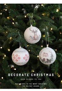Close-up of white glitter Christmas balls with elk and bird patterns on a lit tree