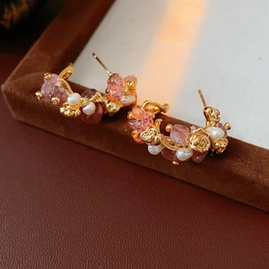 Detailed close-up of gold-plated rose earrings with pink quartz and white pearls