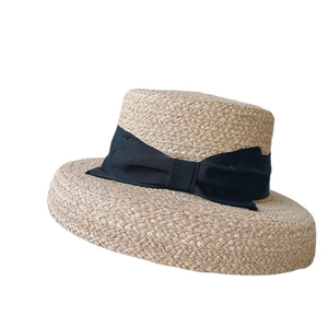 Natural raffia straw sun hat with wide black bow ribbon and flat top brim for summer beach