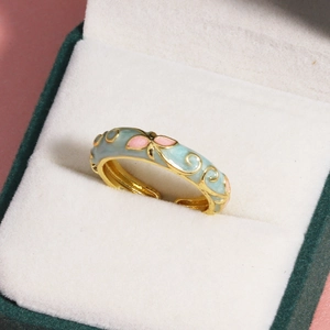 Makro-Detail des goldenen Rings mit blauen Emaille-Wolken und rosa Schmetterlingsmustern