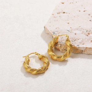 Macro shot of 18K gold plated rope twist knot hoop earrings on a natural stone display