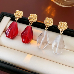 Detailed macro view of gold flower studs with red and clear teardrop crystal pendants