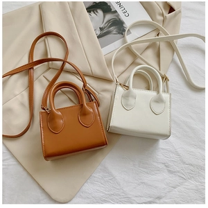 Detailed top view of mini vintage handbags in brown and beige leather over a blazer