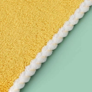 Absorbent yellow coral fleece hand towel with white wavy edges on a mint background