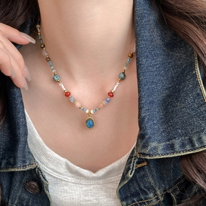 Détail du collier de perles bohème avec pendentif pierre bleue sur un fond de veste en jean