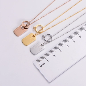 Detail of custom engraved dog tags in gold, rose gold and silver with zircon accent