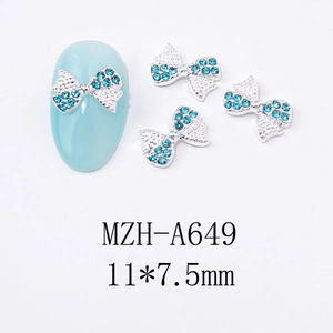 Détail de bijoux d'ongles en forme de nœud argenté avec strass bleu clair 11x7,5mm