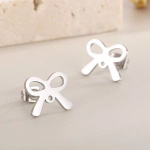 Macro shot of silver-toned hollow bow earrings in polished stainless steel texture