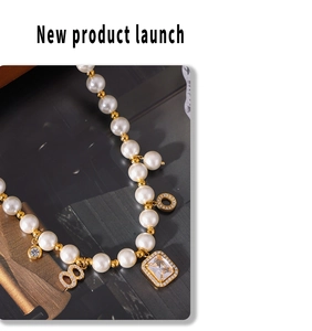 Macro detail of pearl necklace with emerald-cut zircon and gold number 8 pendant charms