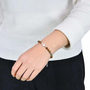 Bracelet en perles d'oeil de tigre marron avec pendentif croix argenté sur poignet