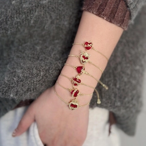 Dettaglio di bracciali dorati regolabili con cuori in zircone rosso