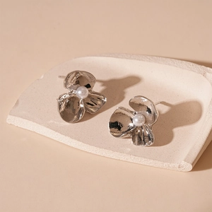 Detail showing silver flower earrings with textured petals and a white pearl center