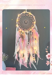 Detail of pink and white feather dreamcatcher with warm LED lighting and lace ribbons