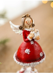 Macro shot of resin angel figurine in red dress with snowflake texture and gold headpiece