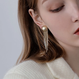 Detail of long gold tassel earrings with matte stud on model for elegant look
