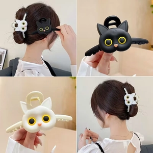 Detailed views of black and white cat-shaped hair claws with large yellow eyes