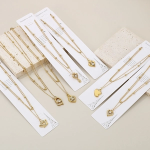 Detail of gold heart pendant necklace with double-layer chain on display card