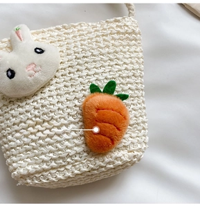 Detail der Stroh-Eimertasche mit Plüschhase und Karotte für Kinder im Urlaub