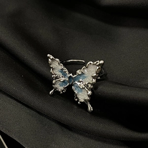 Dettaglio anello a farfalla argento con smalto blu su sfondo di seta nera