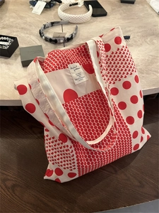 Close-up of red polka dot print on thick off-white canvas tote bag with interior label