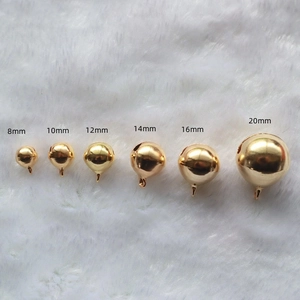 Golden plated round metal bells for DIY crafts in sizes 8mm to 20mm on white plush surface
