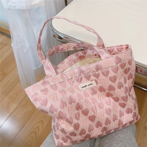 Detail of pink jacquard tote bag featuring a textured heart pattern and simple wish label
