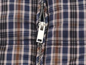 Close-up of blue and brown checkered jacket fabric with a smooth silver metal zipper