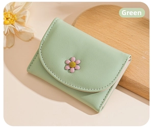 Close-up of mint green trifold wallet with 3D daisy flower and soft leather texture