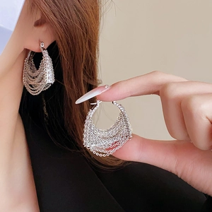 Close-up of silver multilayer chain fringe earrings with rhinestones on model's ear