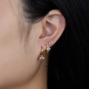 Macro detail of gold evil eye earring set with blue stones and white zircon stones