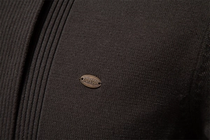 Detail of dark brown fine knit texture with premium metal logo brand badge