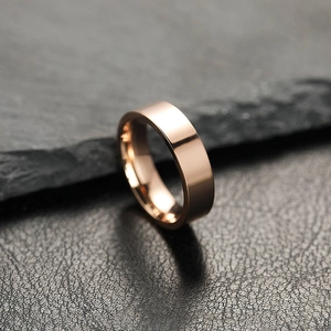 Polished 6mm rose gold stainless steel ring for couples on dark stone background.