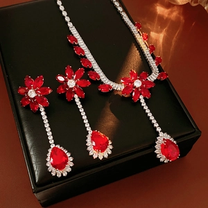 Detailed view of luxury red zircon flower necklace and earrings set on black jewelry box
