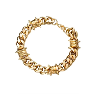 Detailed view of golden Cuban link bracelet with punk barbed wire knots on white background