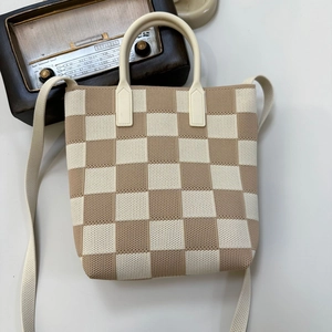 Detail of checkered knit handbag with woven straps and vintage decorative radio