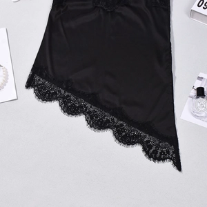 Detail of black satin camisole featuring delicate eyelash lace trim and irregular hemline