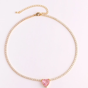 Macro view of gold-plated necklace featuring a sparkling pink heart-shaped stone pendant
