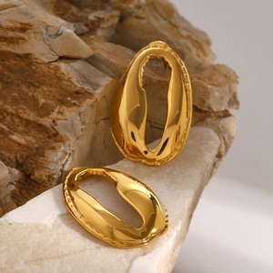 Detailed macro view of 18k gold-plated shell-shaped earrings on a natural stone surface
