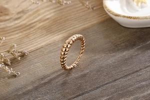 Detail of rose gold croissant ring with ribbed texture on elegant wooden base with flowers