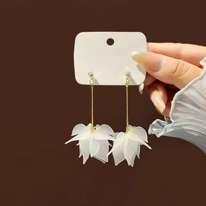 Long white floral drop earrings with gold rod and matte petals held in hand
