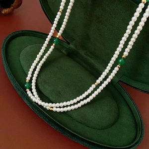 Detail of layered pearl necklace with green agate beads in a luxury green velvet box