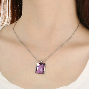 Macro detail of purple square glass pendant on a silver snake chain worn by model
