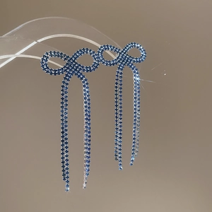 Macro detail of blue crystal bow tassel earrings with sparkling rhinestone fringe