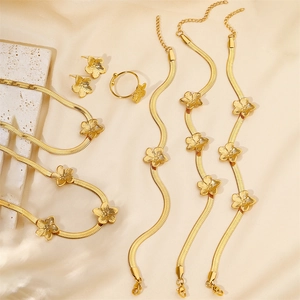 Detailed close-up of gold flower jewelry set with brushed texture on silk background